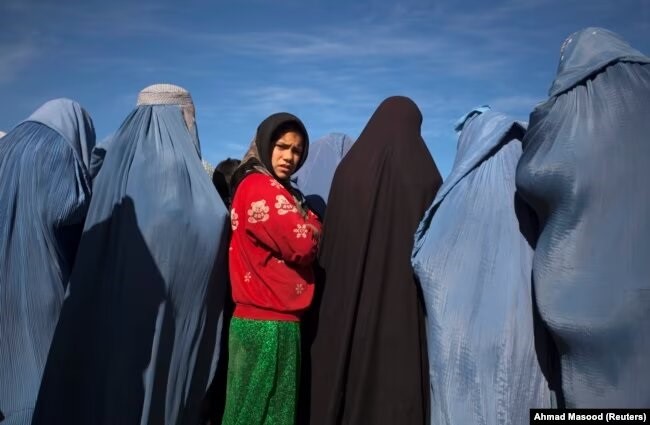 Një vajzë afgane qëndron në mesin e vejushave në veshura me burka